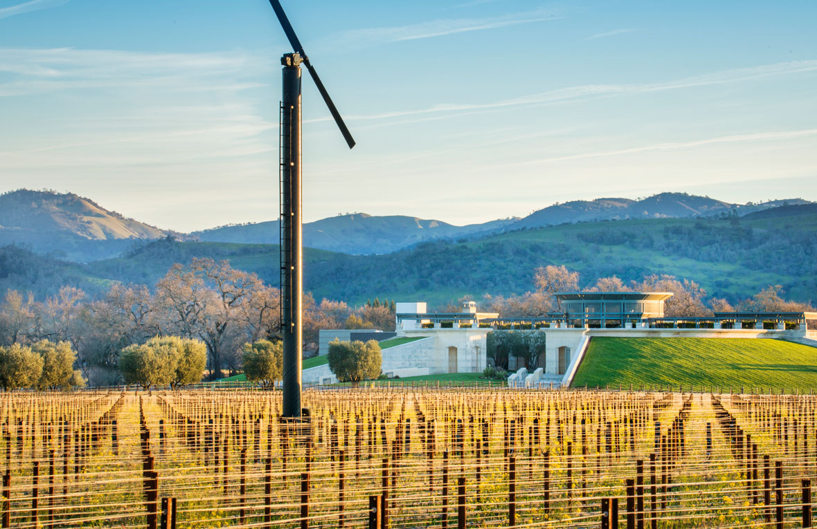 The Opus One building with dormant vines, stakes, and a large silver wind machine in the foreground.